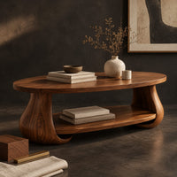 Corner detail of oval coffee table with swelling tulip shaped legs and a lower shelf beside wood, brass and linen samples
