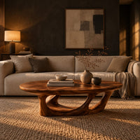 Oval coffee table with a sculpted open loop base in a dark living room at golden hour