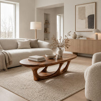 Oval coffee table with a sculpted open loop base in a Scandinavian living room with white walls