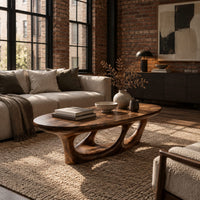 Oval coffee table with a sculpted open loop base in an industrial loft living room with exposed brick