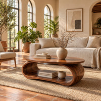 Oval coffee table on a bent loop base with a low shelf inside in a bright living room with arched windows and plants