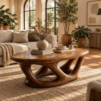 Oval coffee table on interlocking looped wooden legs with a thick top in a bright living room with arched windows and plants