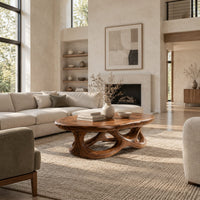 Oval coffee table with a knotted openwork wooden base in a bright open plan living room
