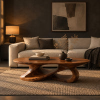 Oval coffee table on a looping ribbon base with open gaps in a dark living room at golden hour