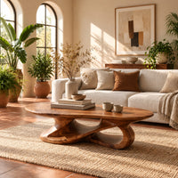 Oval coffee table on a looping ribbon base with open gaps in a bright living room with arched windows and plants