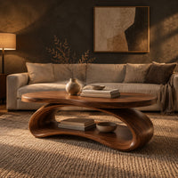Oval wood coffee table on a looping ribbon base with an open lower shelf in a dark living room at golden hour