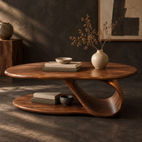 Corner detail of oval coffee table with a low oval shelf and a single scroll support beside wood, brass and linen samples
