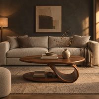 Oval coffee table with a low oval shelf and a single scroll support in a dark living room at golden hour
