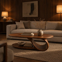 Oval coffee table with a low oval shelf and a single scroll support in an evening living room with walnut wall paneling