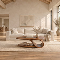 Oval coffee table with a low oval shelf and a single scroll support in a bright open plan living room