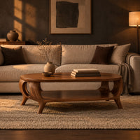 Oval coffee table with a lower shelf and flared legs with circular cutouts in a dark living room at golden hour