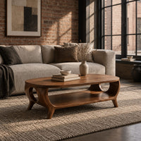 Oval coffee table with a lower shelf and flared legs with circular cutouts in an industrial loft living room with exposed brick