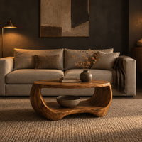 Oval coffee table with a sculpted body and open lower shelf in a dark living room at golden hour
