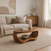 Oval coffee table with a sculpted body and open lower shelf in a Scandinavian living room with white walls