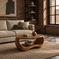 Oval coffee table with a sculpted body and open lower shelf in an industrial loft living room with exposed brick