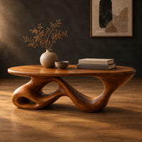 Oval coffee table on a twisting ribbon base with open loops in a dark studio against a charcoal plaster wall