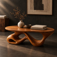 Corner detail of oval coffee table on a twisting ribbon base with open loops beside wood, brass and linen samples