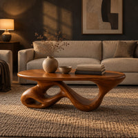 Oval coffee table on a twisting ribbon base with open loops in a dark living room at golden hour