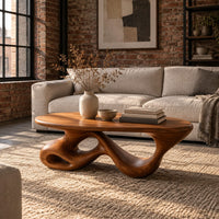 Oval coffee table on a twisting ribbon base with open loops in an industrial loft living room with exposed brick