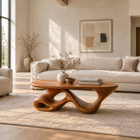 Oval coffee table on a twisting ribbon base with open loops in a bright open plan living room