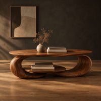 Oval coffee table on two curled legs with a small oval shelf below in a dark studio against a charcoal plaster wall