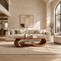 Oval coffee table on two curled legs with a small oval shelf below in a bright open plan living room