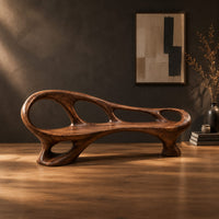 Long wooden bench with oval cutouts along the back rail and a flowing frame in a dark studio against a charcoal plaster wall
