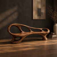 Long wooden bench with oval cutouts along the back rail and a flowing frame, three-quarter view showing the grain