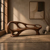 Long wooden bench with oval cutouts along the back rail and a flowing frame in an industrial loft entryway with exposed brick