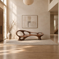 Long wooden bench with oval cutouts along the back rail and a flowing frame in a bright open plan entryway