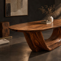 Corner detail of oval dining table on a U shaped sculpted pedestal base beside wood, brass and linen samples