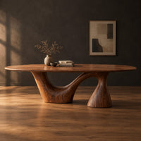 Oval dining table on a sweeping arm base and a tall cone column in a dark studio against a charcoal plaster wall