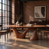 Oval dining table on a sweeping arm base and a tall cone column in an industrial loft dining room with exposed brick