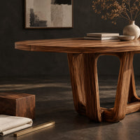Corner detail of oval dining table with sculpted arched legs joined by a low floor loop beside wood, brass and linen samples