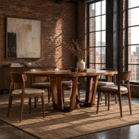 Oval dining table with sculpted arched legs joined by a low floor loop in an industrial loft dining room with exposed brick