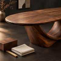Corner detail of oval dining table on a sculpted crescent base beside wood, brass and linen samples
