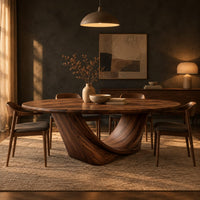 Oval dining table on a sculpted crescent base in a dark dining room at golden hour