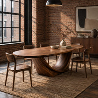 Oval dining table on a sculpted crescent base in an industrial loft dining room with exposed brick
