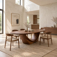 Oval dining table on a sculpted crescent base in a bright open plan dining room
