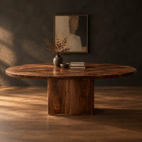Oval dining table with a thick edge and two broad slab legs in a dark studio against a charcoal plaster wall