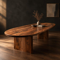 Oval dining table with a thick edge and two broad slab legs, three-quarter view showing the grain