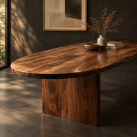 Corner detail of oval dining table with a thick edge and two broad slab legs beside wood, brass and linen samples