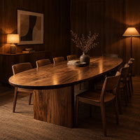 Oval dining table with a thick edge and two broad slab legs in an evening dining room with walnut wall paneling