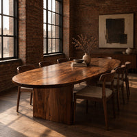 Oval dining table with a thick edge and two broad slab legs in an industrial loft dining room with exposed brick