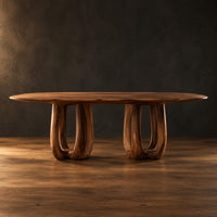 Oval dining table on two pedestal bases with tall arched openings in a dark studio against a charcoal plaster wall