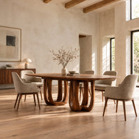 Oval dining table on two pedestal bases with tall arched openings in a bright open plan dining room