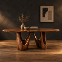 Oval dining table with two sculpted arch pedestals in a dark studio against a charcoal plaster wall
