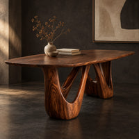 Corner detail of oval dining table with two sculpted arch pedestals beside wood, brass and linen samples