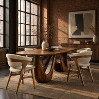 Oval dining table with two sculpted arch pedestals in an industrial loft dining room with exposed brick