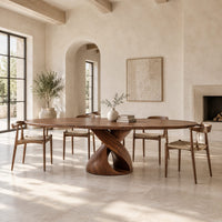 Oval dining table with a twisting ribbon pedestal and a hollow center in a bright open plan dining room